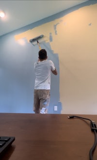 a man painting a wall in an office