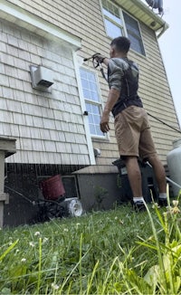 a man spraying a house with a pressure washer